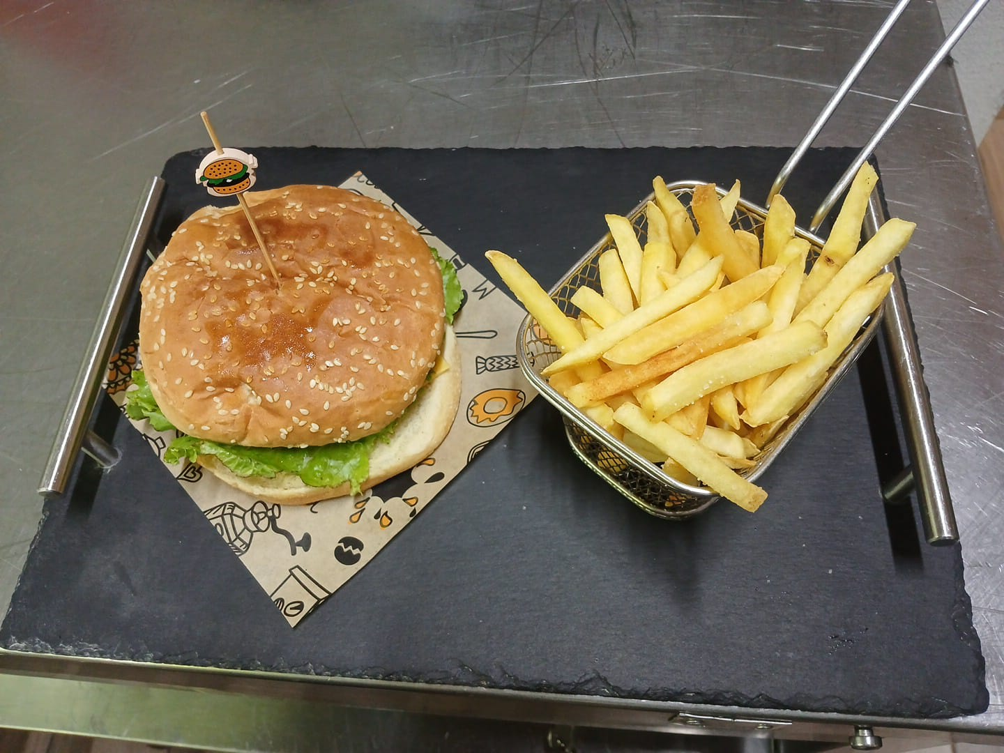 Hamburguesa artesanal con papas fritas presentada en bandeja