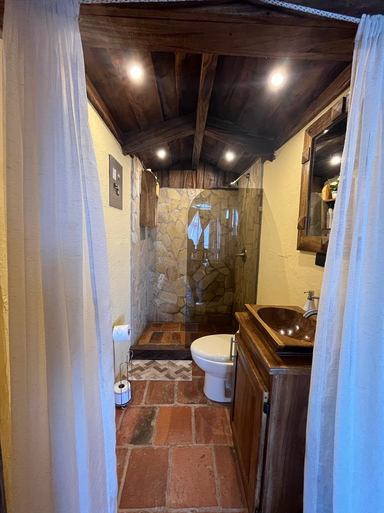 Baño con ducha de piedra y acabados en madera