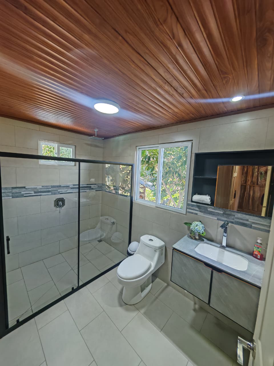 Baño moderno con ducha de vidrio y techo de madera