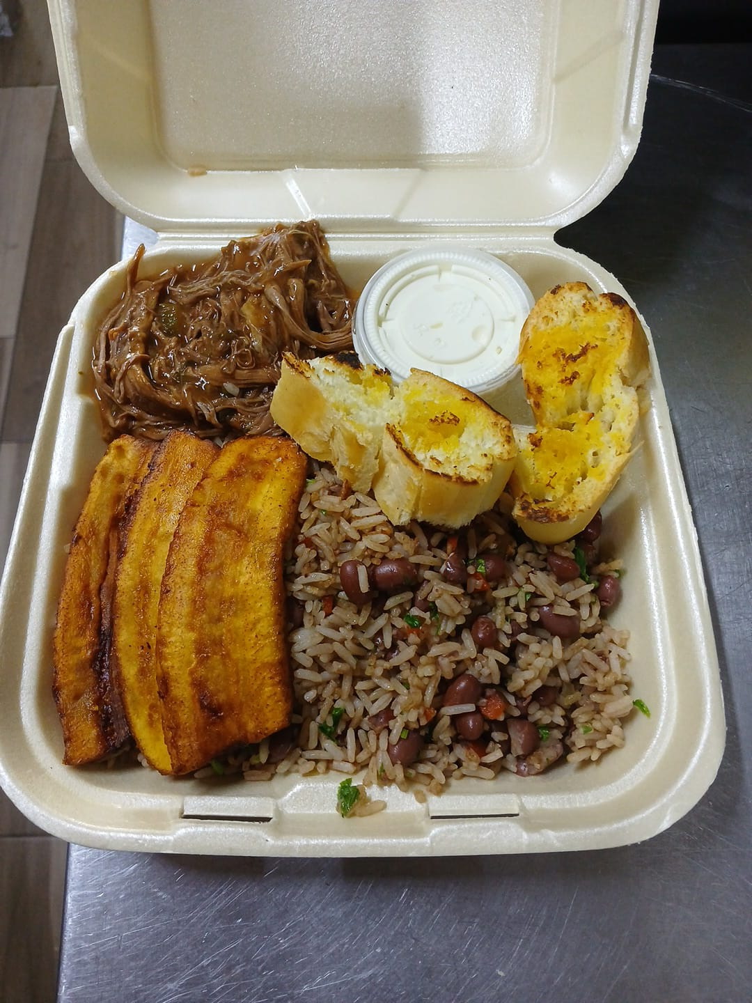 Arroz con frijoles, carne mechada, pan con ajo y plátano maduro