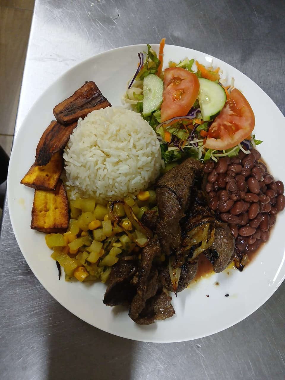 Casado con arroz, frijoles, ensalada, plátano maduro y carne servido en Antojitos de Mi Alma