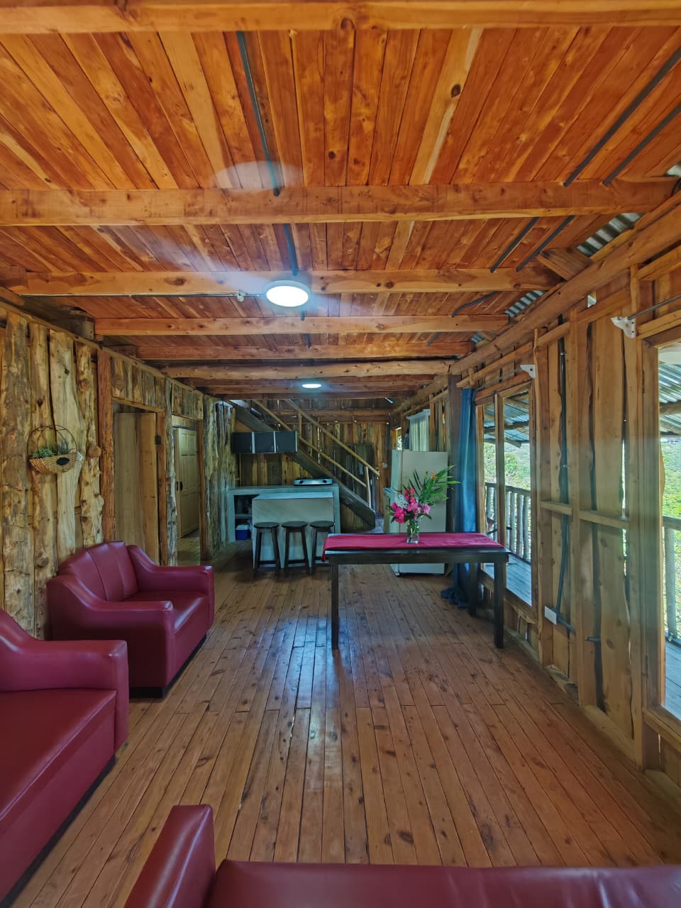 Sala amplia con muebles rojos y techo de madera