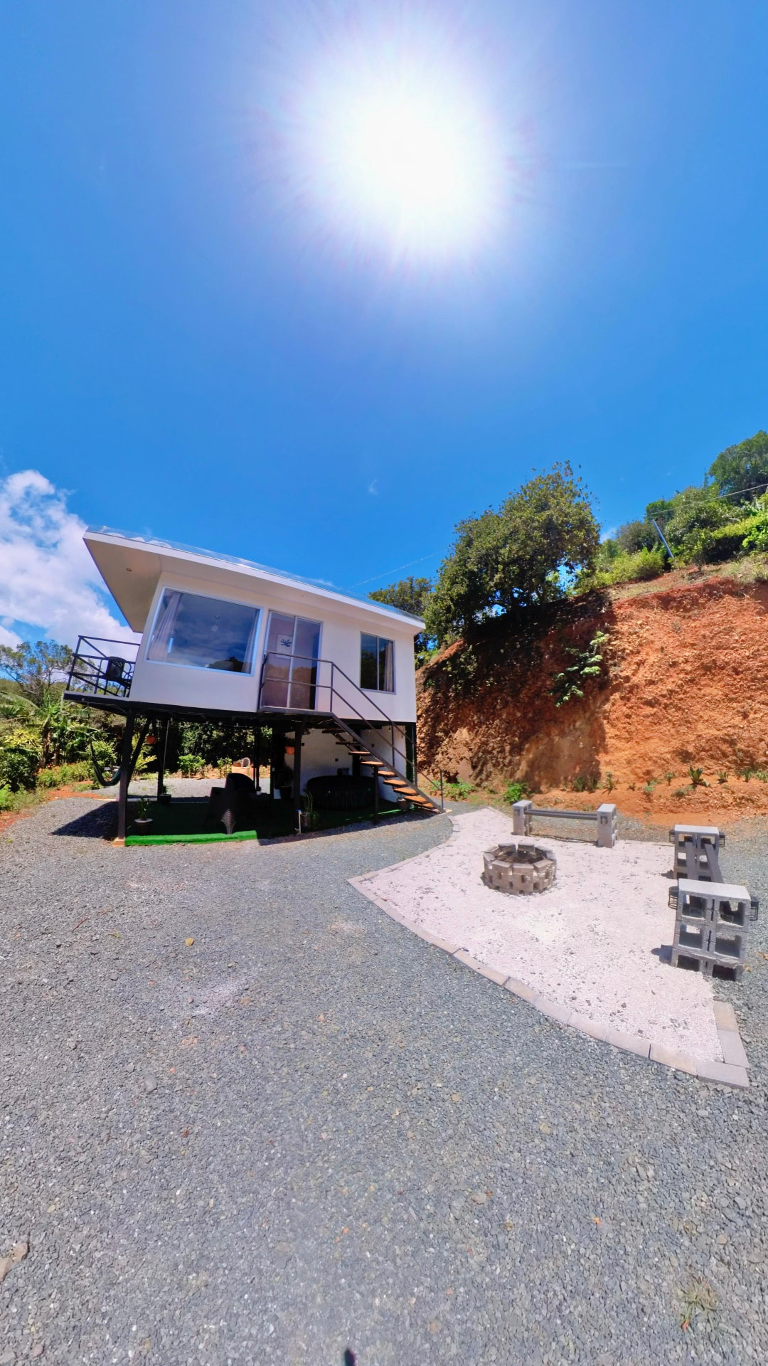 Fachada de la villa elevada con área de fogata